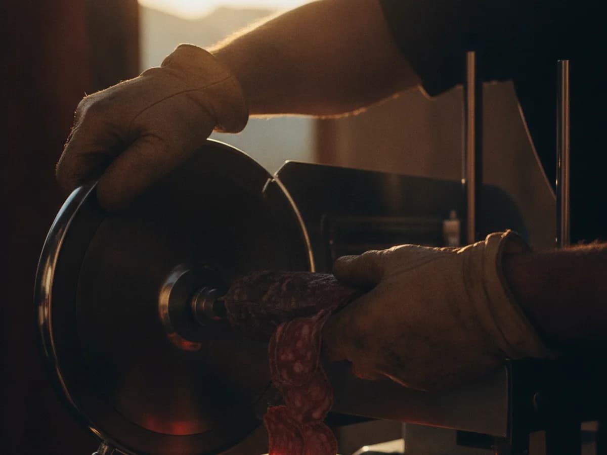 Hände beim Aufschneiden von Salumi an der Maschine